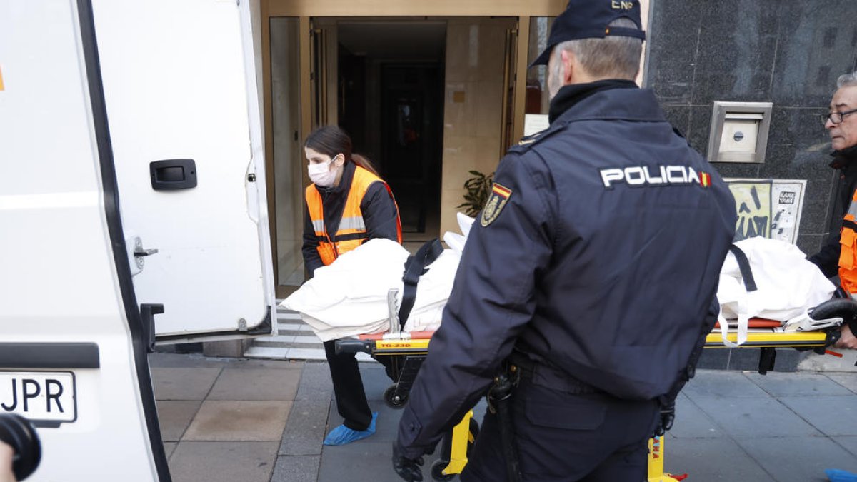 Empleats de la funerària es fan càrrec del cos de la dona.