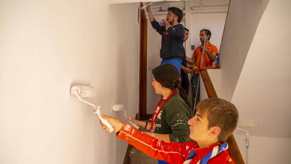Un grup de joves voluntaris pintant l’escala d’un bloc de pisos a la Mariola.