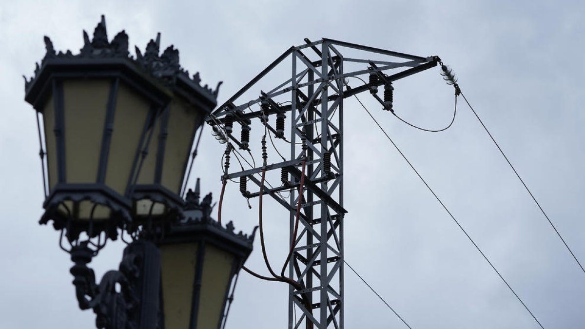 Imagen de una farola junto a una torre eléctricca.