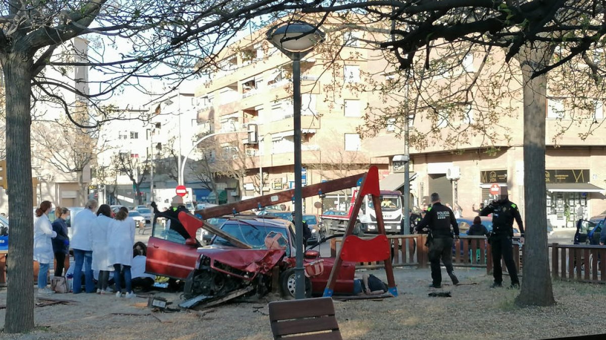 Agentes de la Guardia Urbana y sanitarios del CAP atendieron ayer a los ocupantes del vehículo que se empotró contra el parque.