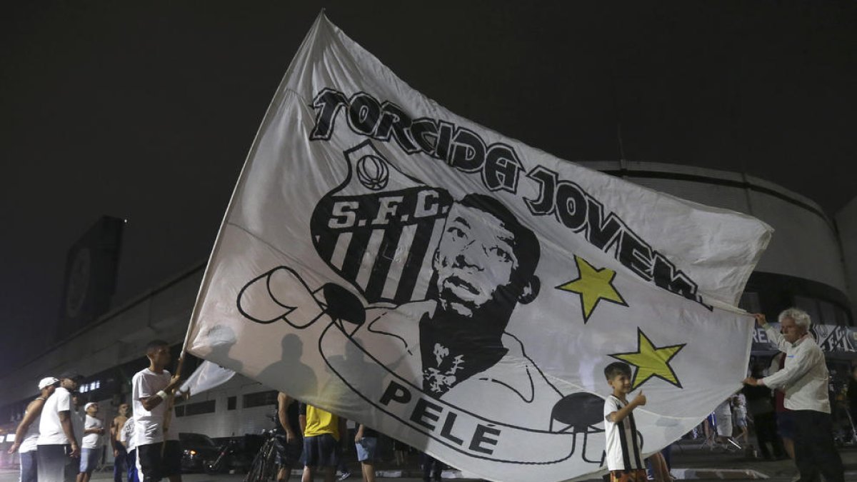 Aficionados del Santos cerca del estadio enarbolan una gran bandera con la efigie de Pelé.