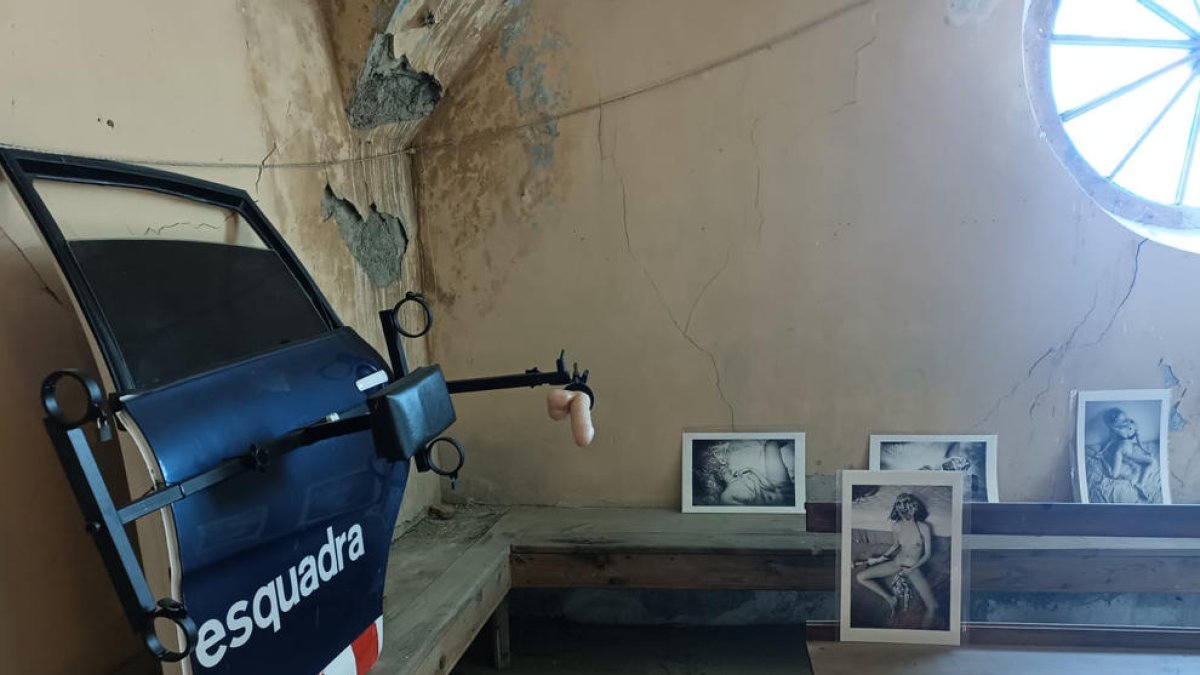 Una porta policial ‘tunejada’ i fotos de nus sobre bancs de l’església a l’exposició.