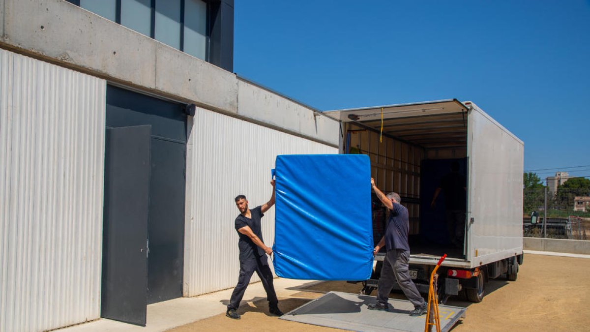 Operarios llevan una colchoneta al nuevo colegio Minerva.