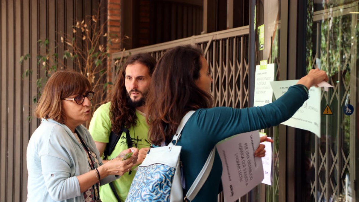 Varios miembros de USTEC ante el departamento de Educación en Barcelona enganchando carteles en las puertas.