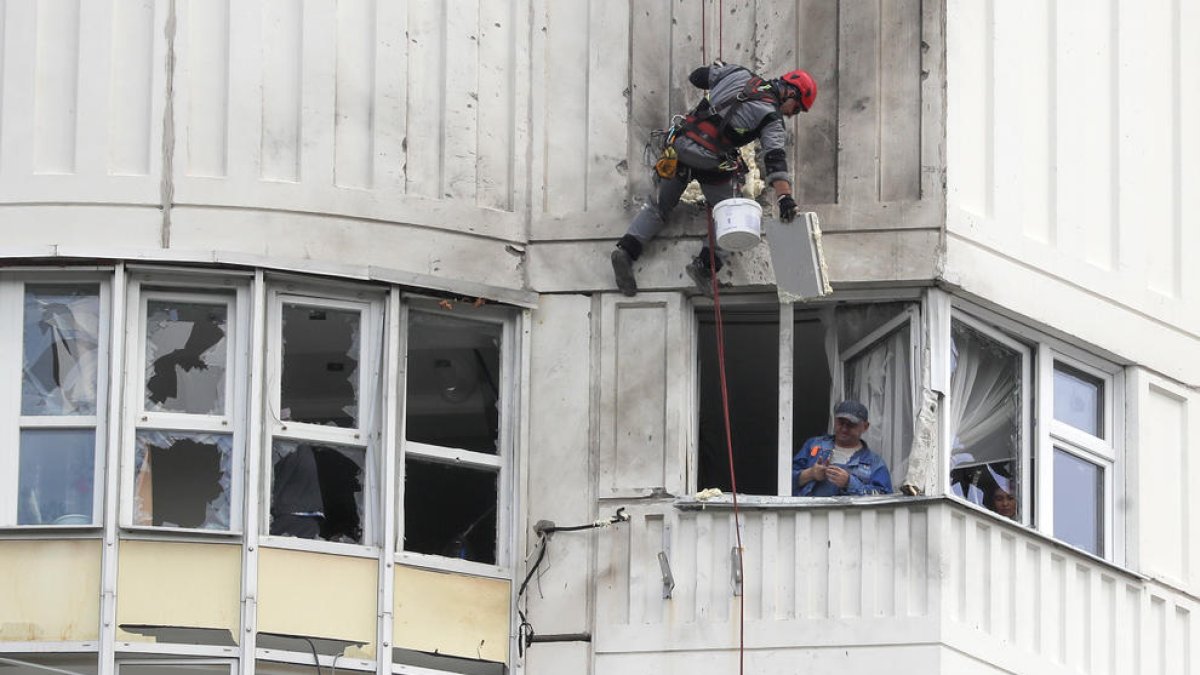 Dos treballadors reparen un edifici residencial afectat per l’atac a Moscou.