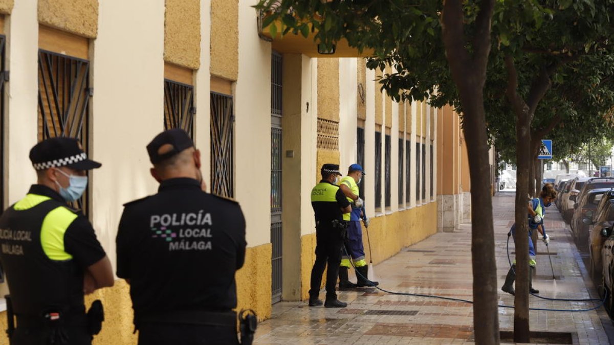 Dos operaris netegen la porta del col·legi de Màlaga davant la qual es va cometre el crim.