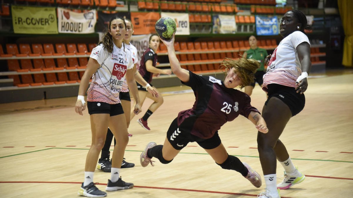 La jugadora del Lleida Handbol, Cati Casasola, lanza la pelota tras irse de dos jugadoras rivales.