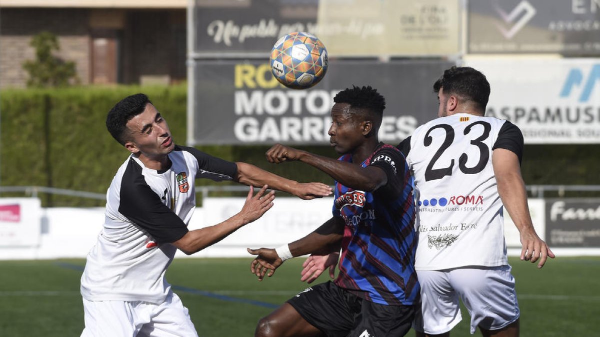 Un jugador del Tàrrega intenta controlar el balón entre dos futbolistas del Borges.