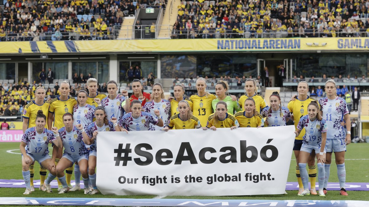 Les jugadores d’ambdós equips posen amb una pancarta en la qual es llegeix