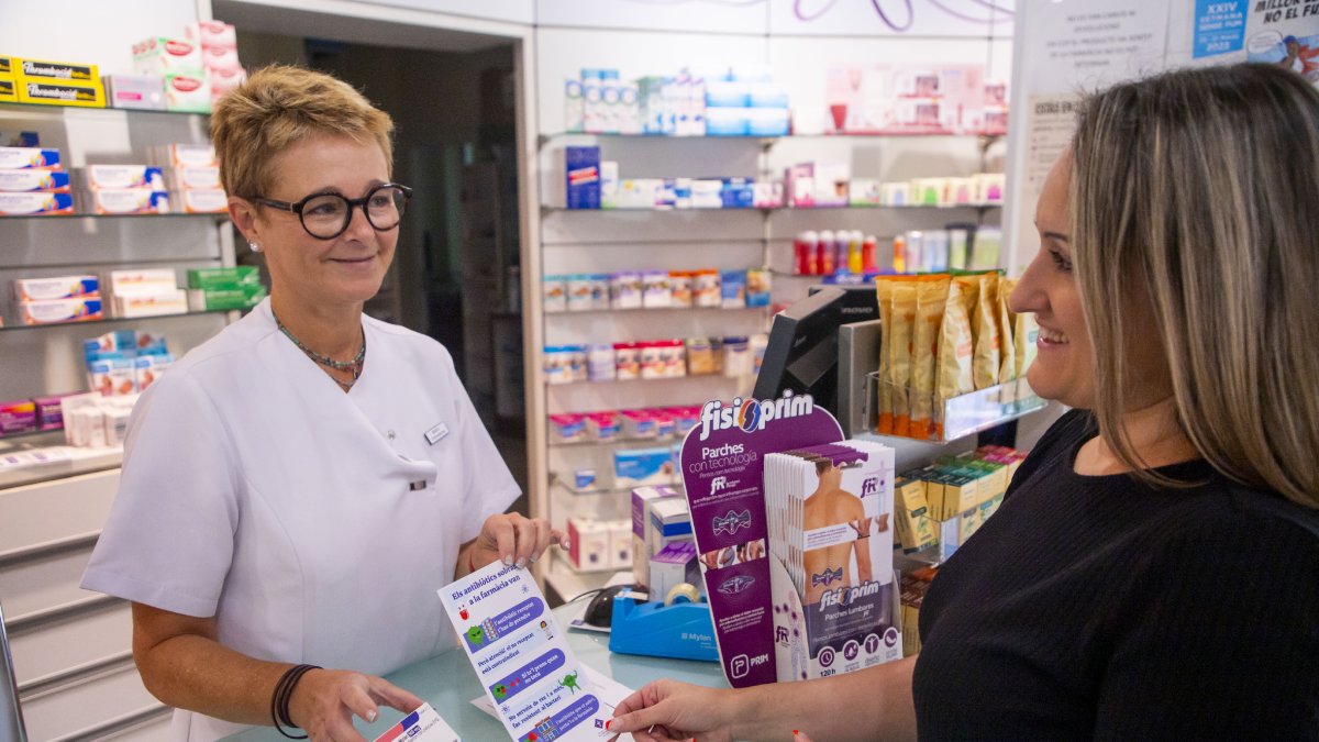 Entrega de un envase de antibióticos con la pegatina y la infografía a una clienta en la farmacia Delmàs. - GERARD HOYAS
