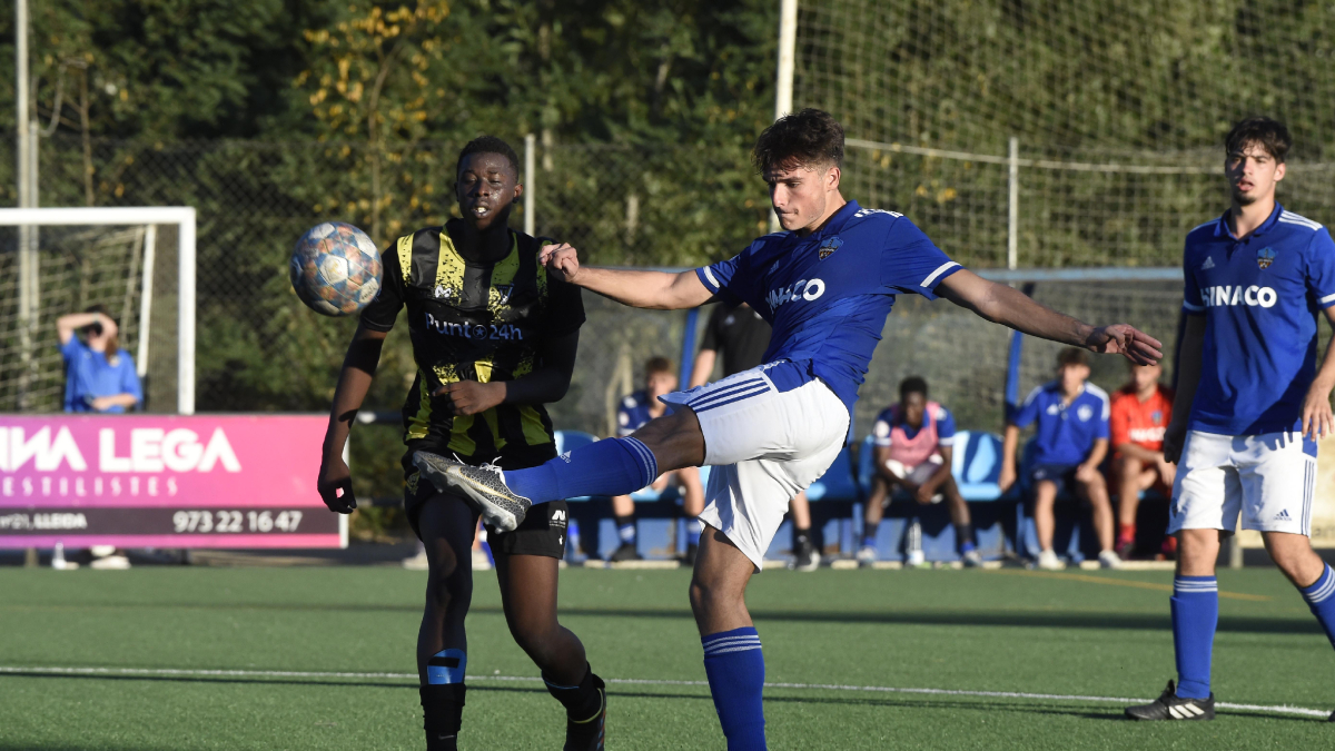 Un jugador del Lleida B despeja el esférico dentro del círculo central ante la presión de un rival. - SANTI IGLESIAS