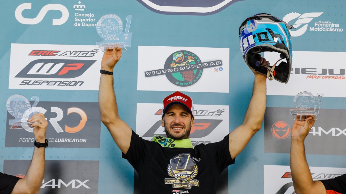 Jaume Betriu celebra su título en el podio levantando el trofeo y su casco. - ROVIRAMEDIA
