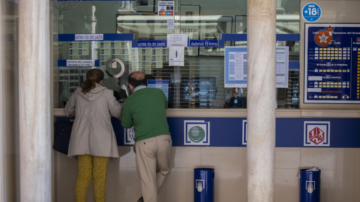 Dos personas comprando lotería en una administración.