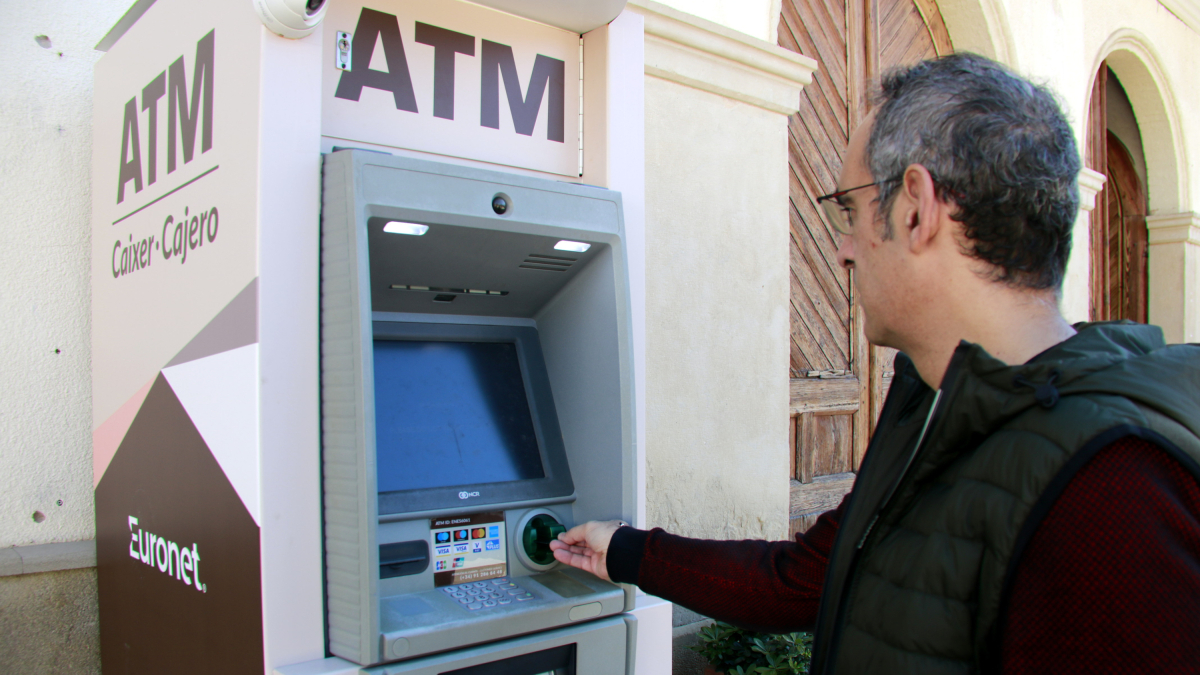 Un hombre saca dinero del nuevo cajero automático de Castellnou de Seana