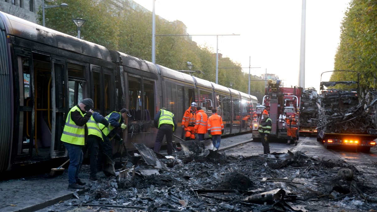 Operaris municipals netegen les restes d’un vehicle calcinat pels aldarulls de dijous. - EUROPA PRESS