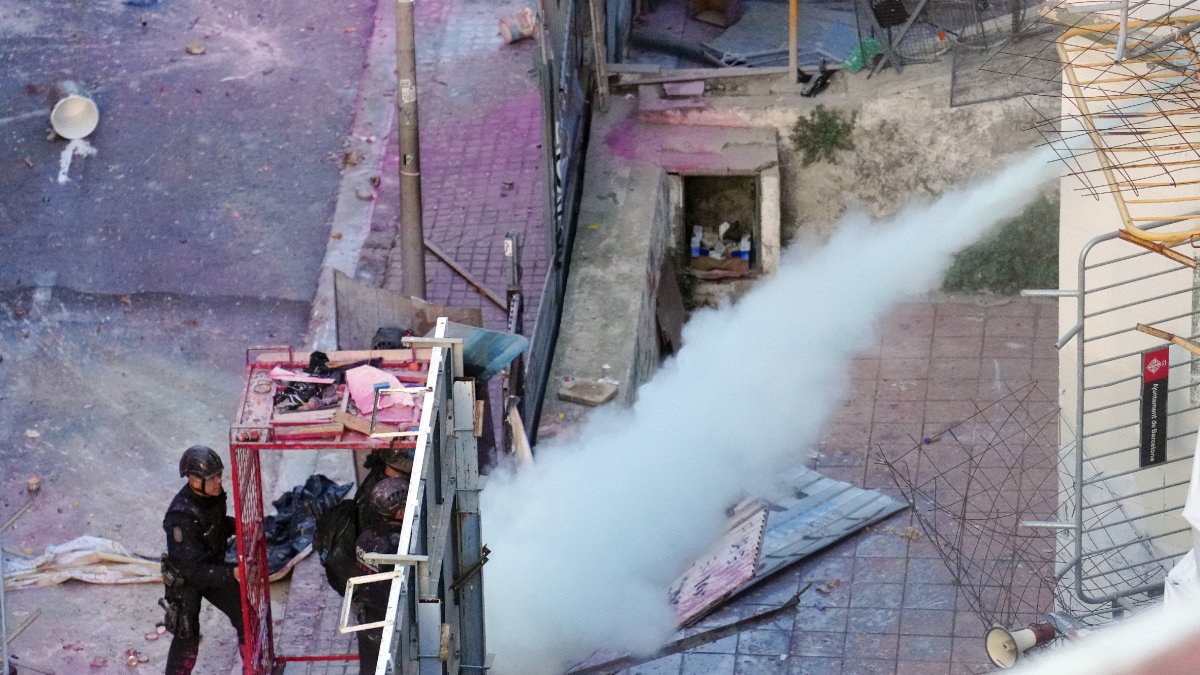 Els mossos a la gàbia per protegir-se mentre els okupes de la Bonanova els ruixen amb un extintor. - EFE