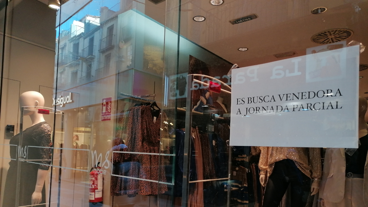 Un cartell en una botiga que busca venedora.