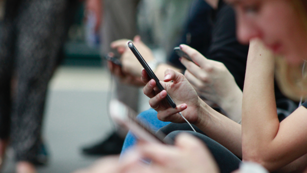 Imatge d’arxiu de diverses persones utilitzant el telèfon mòbil.