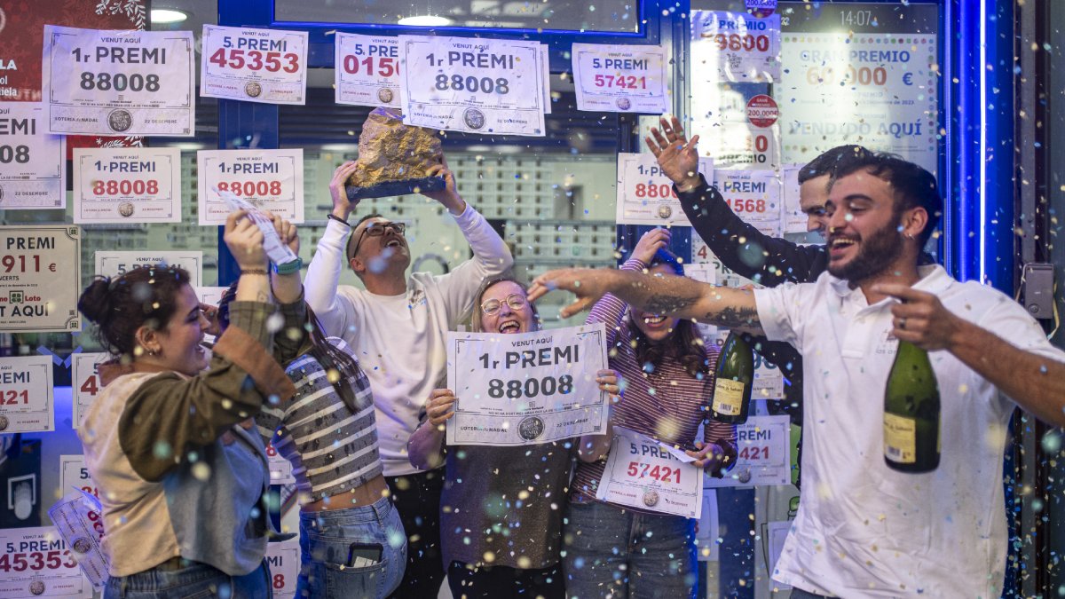 Víctor Fernández sostiene la “piedra de oro”, a la que atribuye su suerte, y celebra junto a algunos agraciados en su administración. - EUROPA PRESS