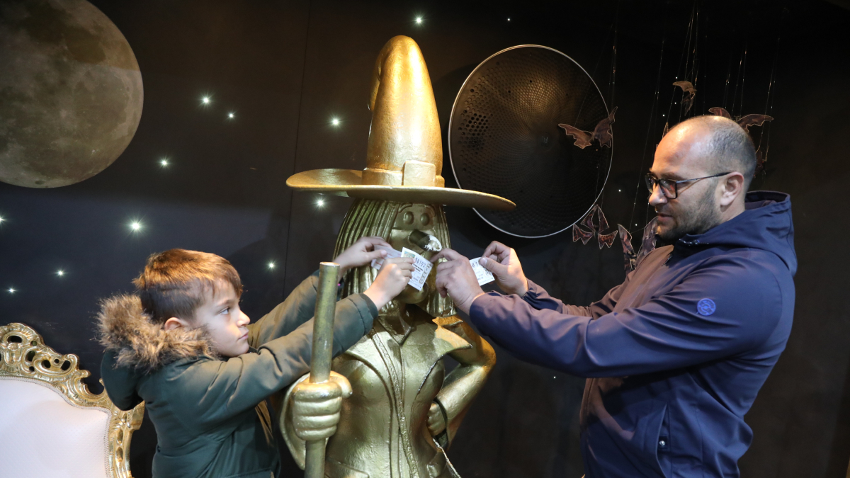 Uno pare y su hijo, con la emblemática estatua de La Bruixa d'Or de Sort.