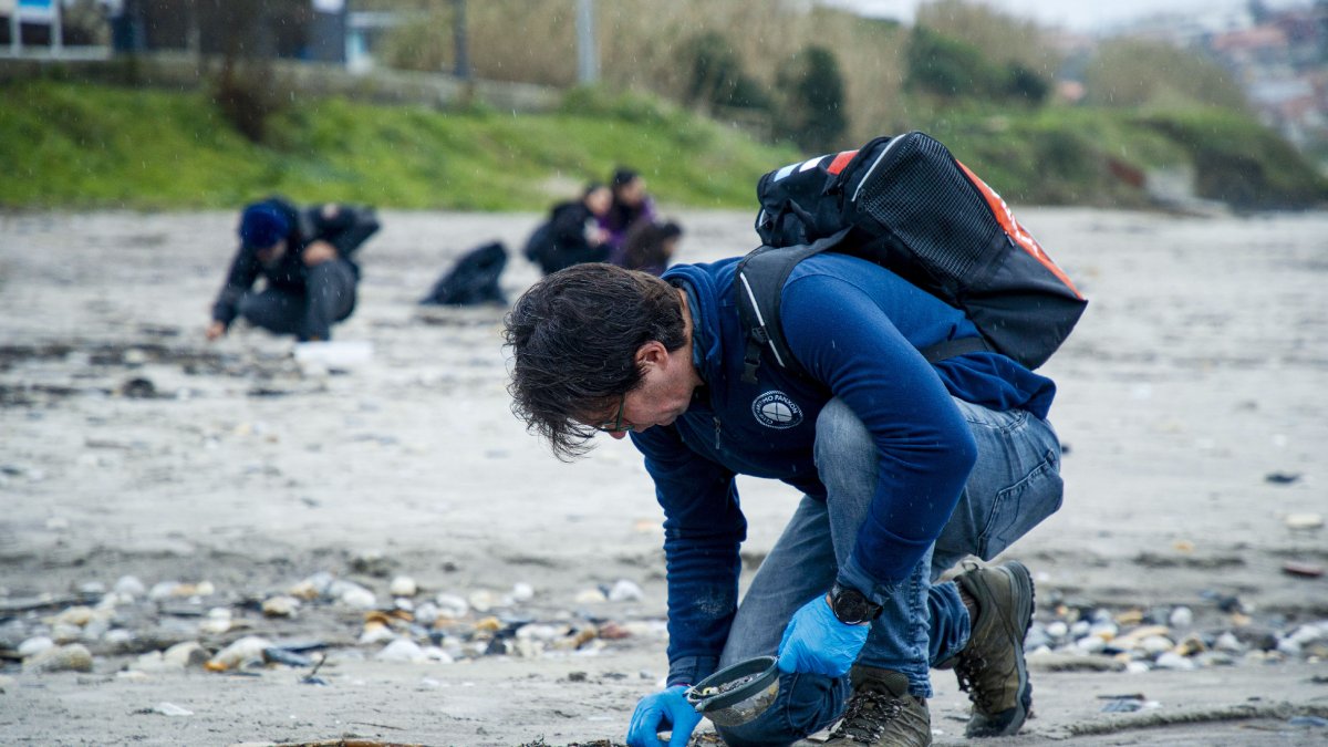 Un hombre recoge pellets de plástico en una playa de A Coruña. - EFE
