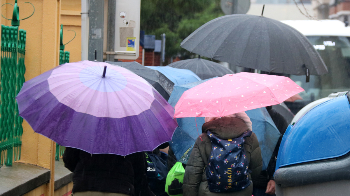 Una multitud de personas anda bajo la lluvia con paraguas
