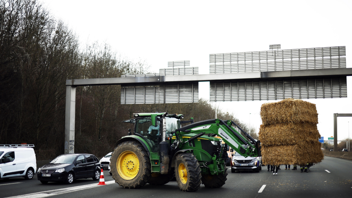 Un tractor descarga heno en medio de la carretera durante el bloqueo de la autopista A15 en Argenteuil. - EFE/EPA/YOAN VALAT