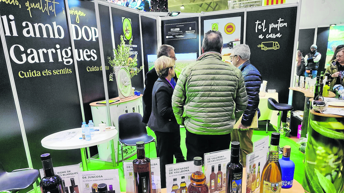Estand de la DOP en la Fira de l’Oli. Sobre la mesa, un cartel reivindicativo con el nombre GARR***ES. - MOLÍ DELS TORMS / OLICATESSEN