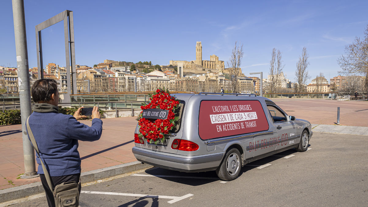 Un ciudadano fotografía el coche fúnebre de la campaña de Trànsit ayer a su paso por Lleida ciudad. - JORDI ECHEVARRIA