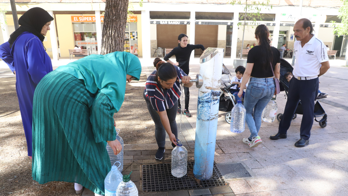 Los vecinos del bloque del Secà sin suministro llenan garrafas de agua en una fuente del barrio.