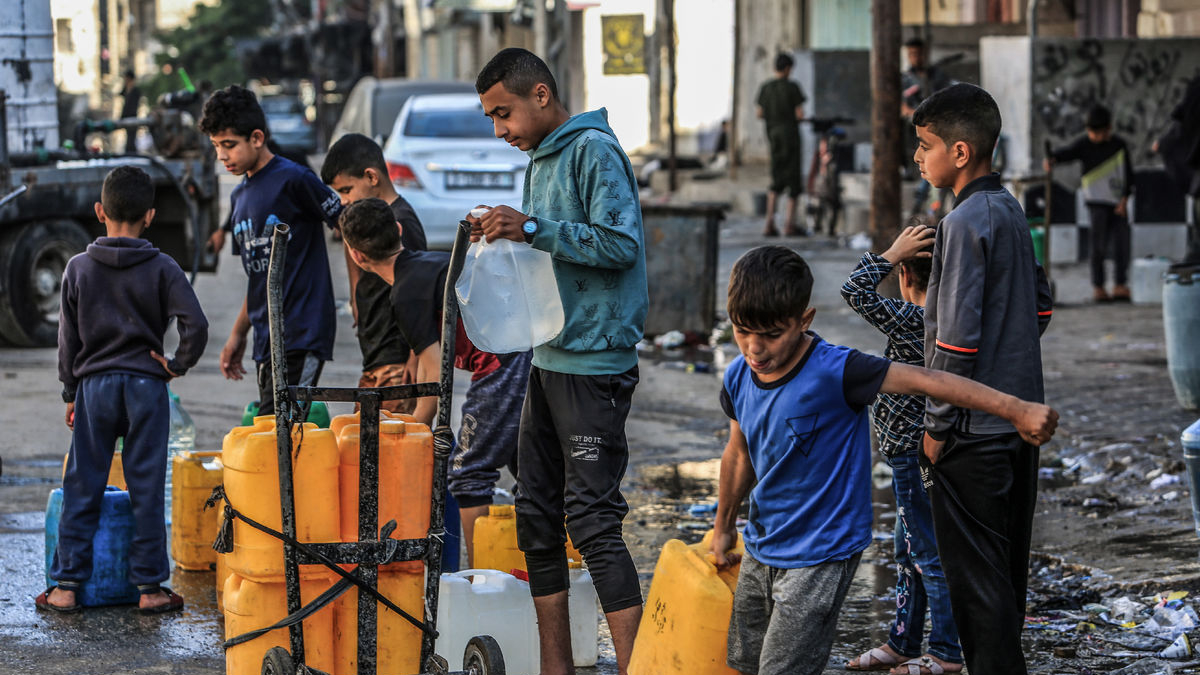 Palestinos, incluidos niños, hacen cola con contenedores de agua potable para llenarlos en Rafah. - ABED RAHIM KHATIB / DPA