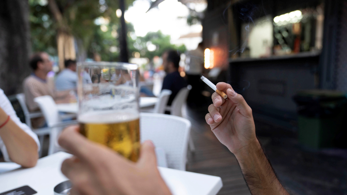 Una persona sosté un cigarro a la terrassa en un bar.