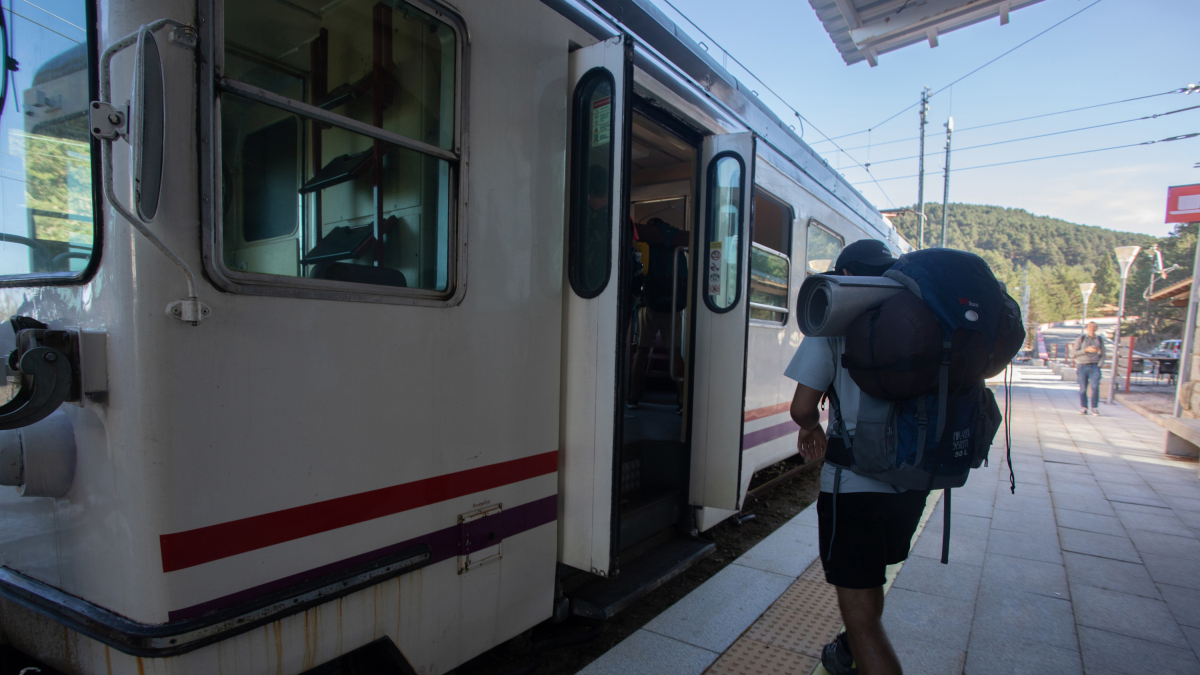 Un joven con mochila subiendo a un tren.