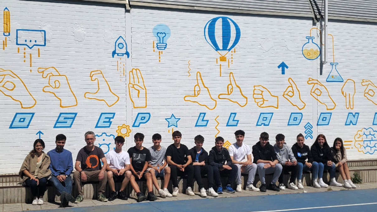 Los alumnos y el profesor que han pintado el mural de manos que ‘dibujan’ los signos que forman el nombre de Josep Lladonosa. - INSTITUT RONDA