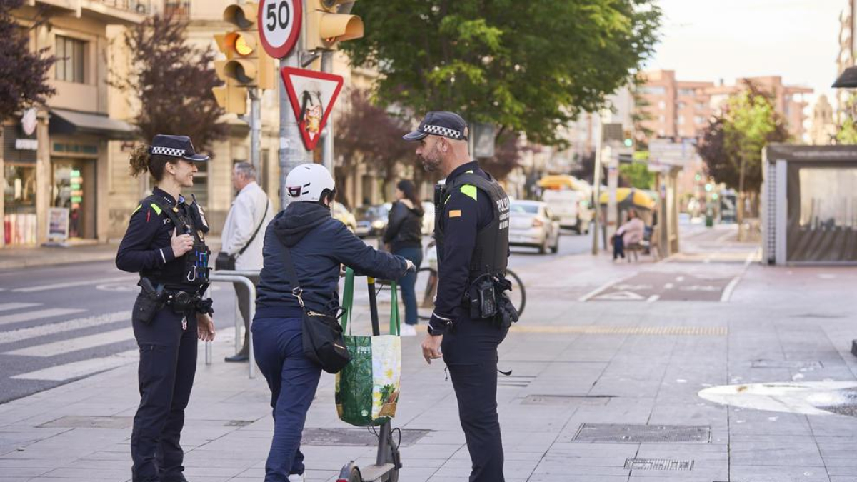 Dos agentes de la Guardia Urbana de Lleida y una persona con un patinete eléctrico en la Plaza Ricard Viñes de Lleida.