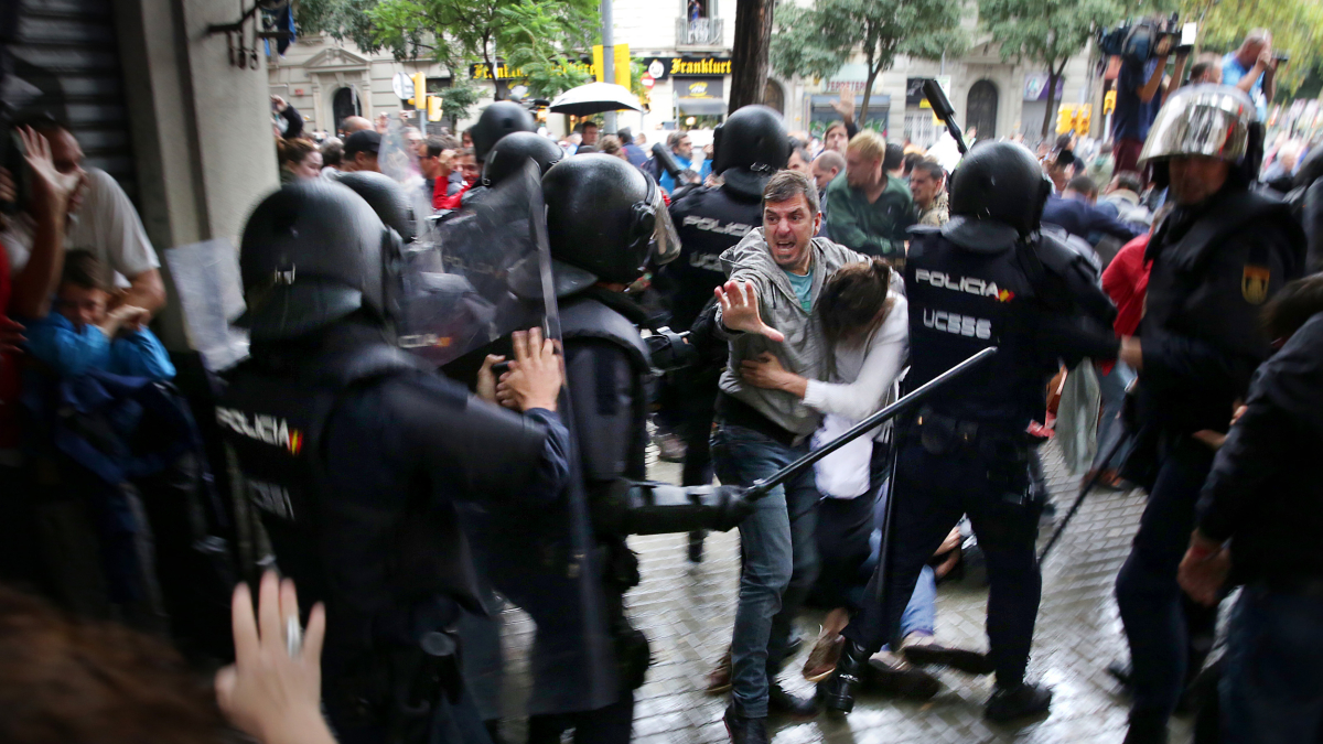 Un hombre intenta proteger a una mujer de los porrazos de agentes antidisturbios de la policía española el 1 de octubre del 2017.