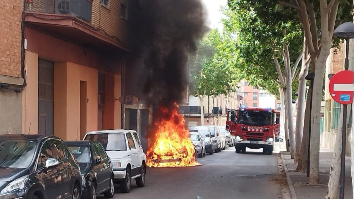 El cotxe en flames i una dotació dels Bombers al carrer Conca de Barberà de Lleida.