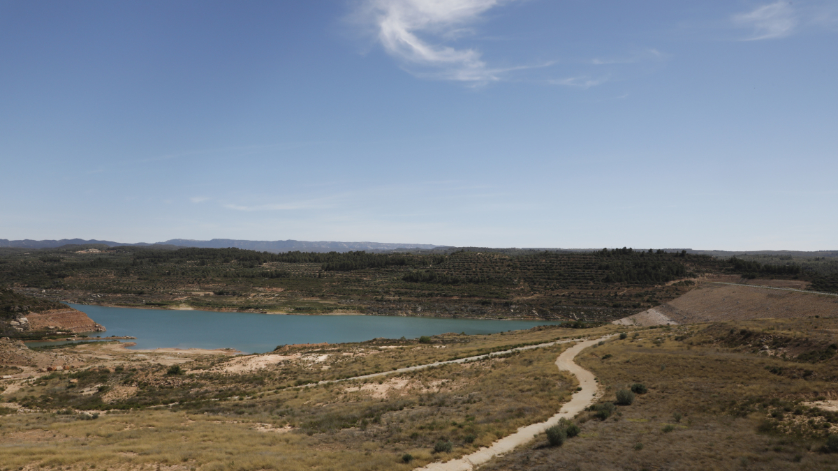 La presa de tierra, a la derecha, que retiene actualmente menos de seis hectómetros cúbicos de agua.