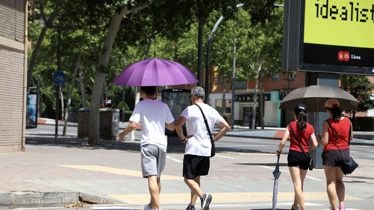 Transeúntes se protegen con paraguas del sol, ayer en Lleida. - MAGDALENA ALTISENT