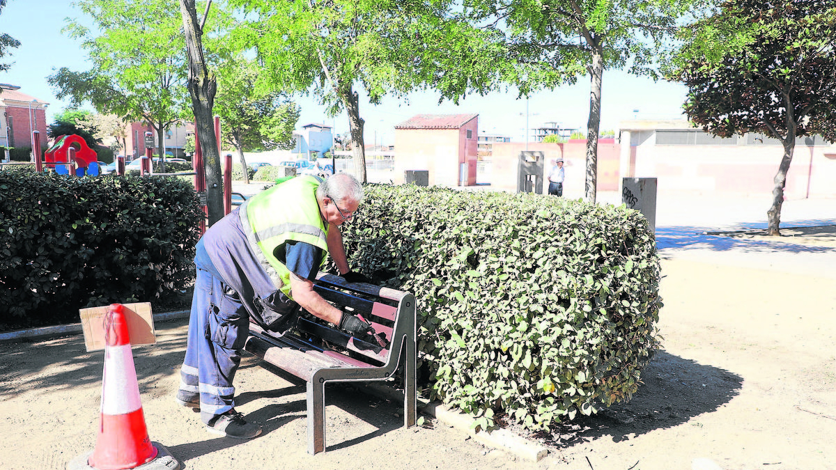 Un operario adecentando un banco de un parque de La Bordeta ayer durante la campaña Barri a Barri. - MAGDALENA ALTISENT
