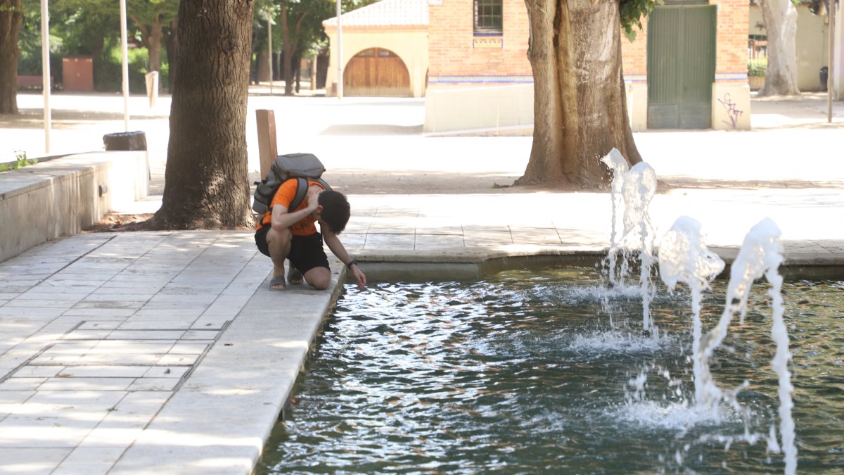 Una persona es refresca als Camps Elisis de Lleida.