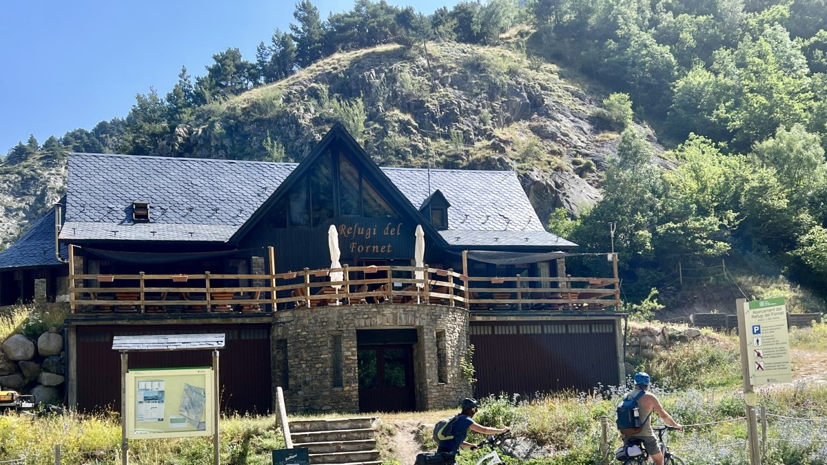 Dos ciclistas pasando por delante del Refugio del Fornet, en Alt Àneu.