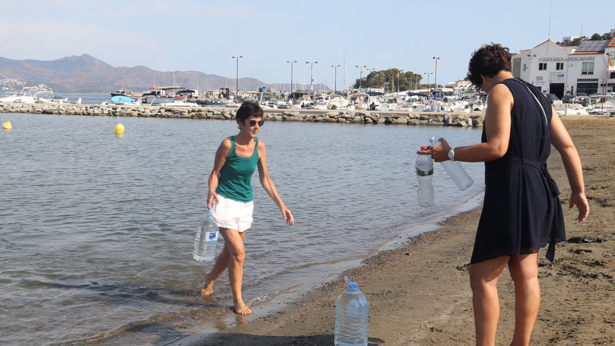 Dos dones omplen botelles i garrafes amb aigua de mar. - ALEXIS FREIXAS/ACN