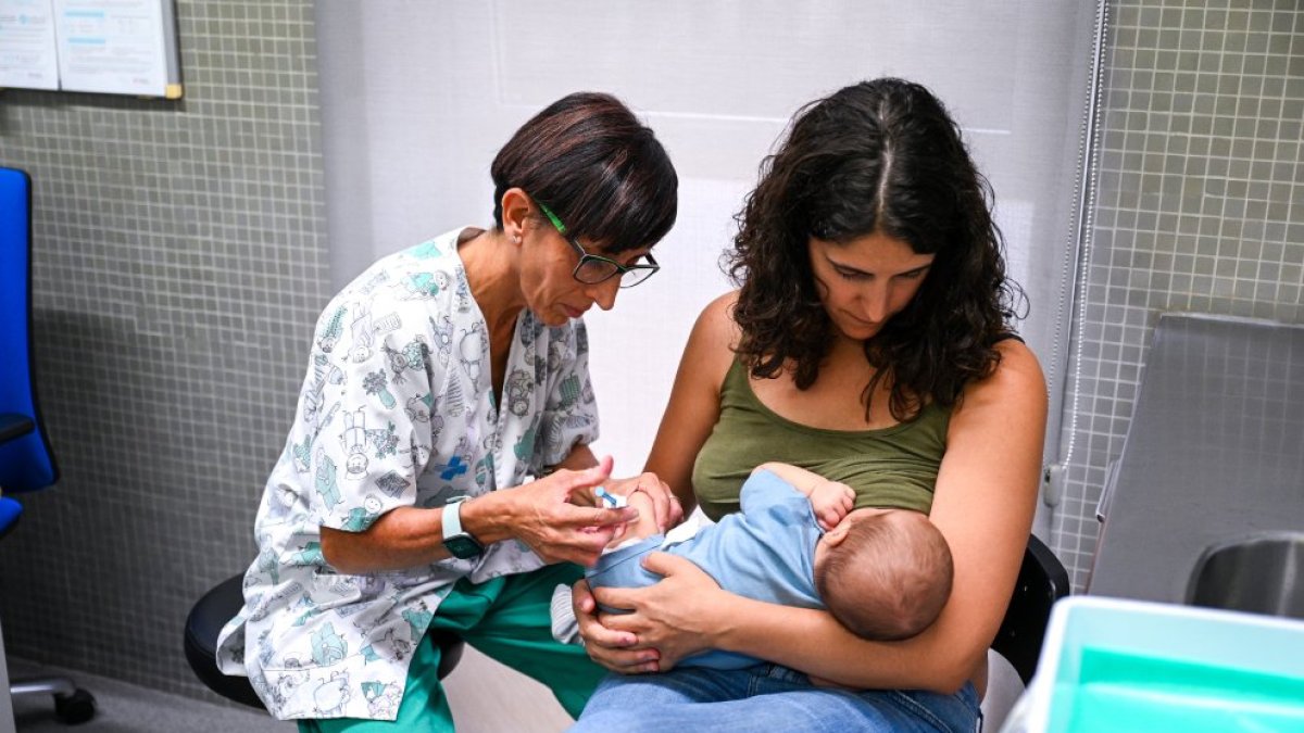 Una enfermera inocula una vacuna a un bebé en un CAP.