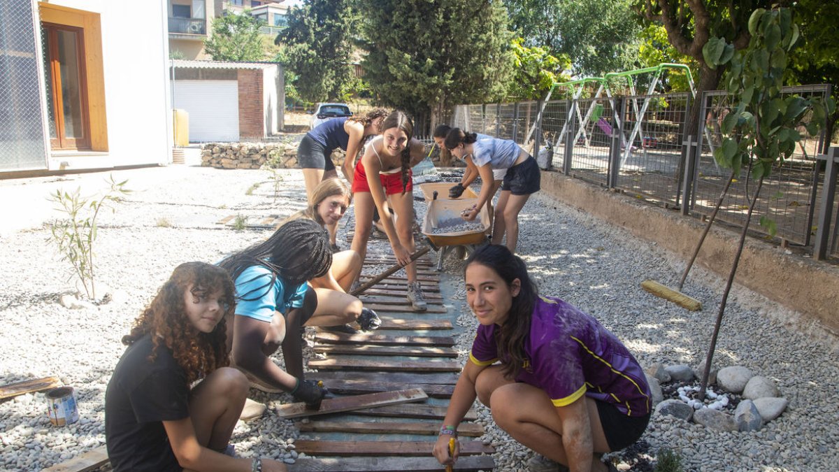 Algunes de les joves ultimant la pintura a les peces de fusta que conformen el nou camí. - LAIA PEDRÓS