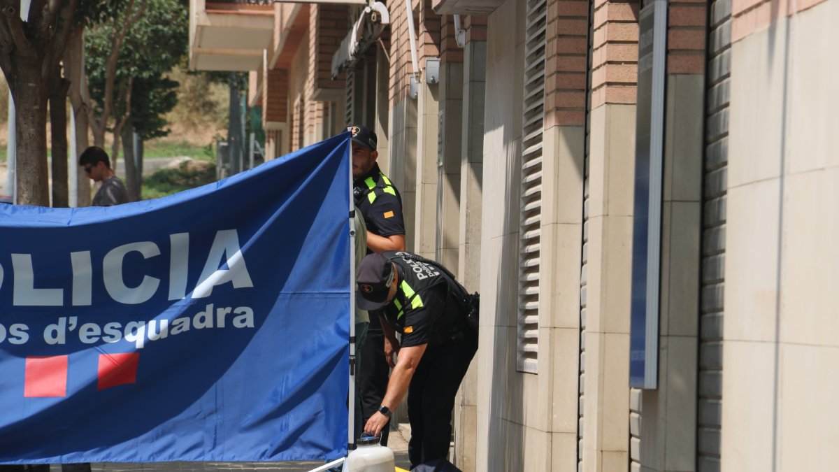 La policía coloca una lona para tapar la zona de la entrada del piso donde se ha cometido el asesinato de una mujer en Rubí