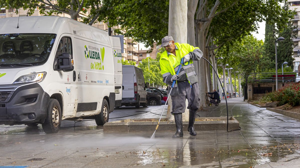 Un operario de Ilnet, limpiando con agua una acera. - JORDI ECHEVARRIA