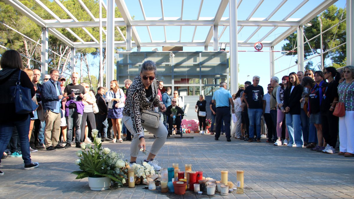 Una mujer depositando claveles en el memorial para homenajear a la cocinera asesinada por un preso en la prisión de Mas d'Enric hace seis meses.