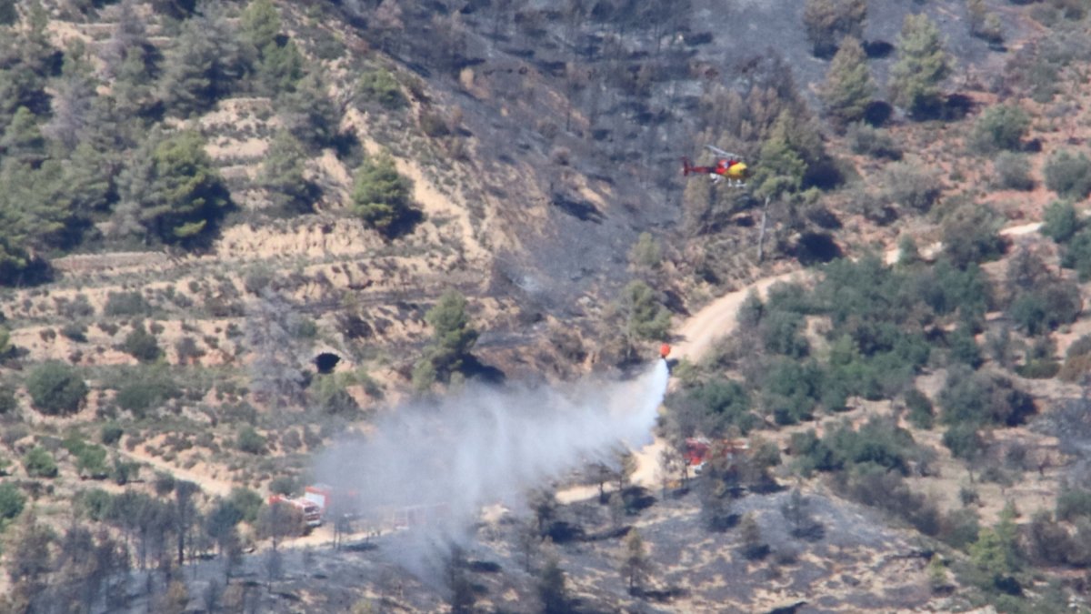 Un helicòpter dels Bombers descarrega aigua al flanc dret de l'incendi de Cabacés, prop de Mas del Roger, vist des de la Figuera.