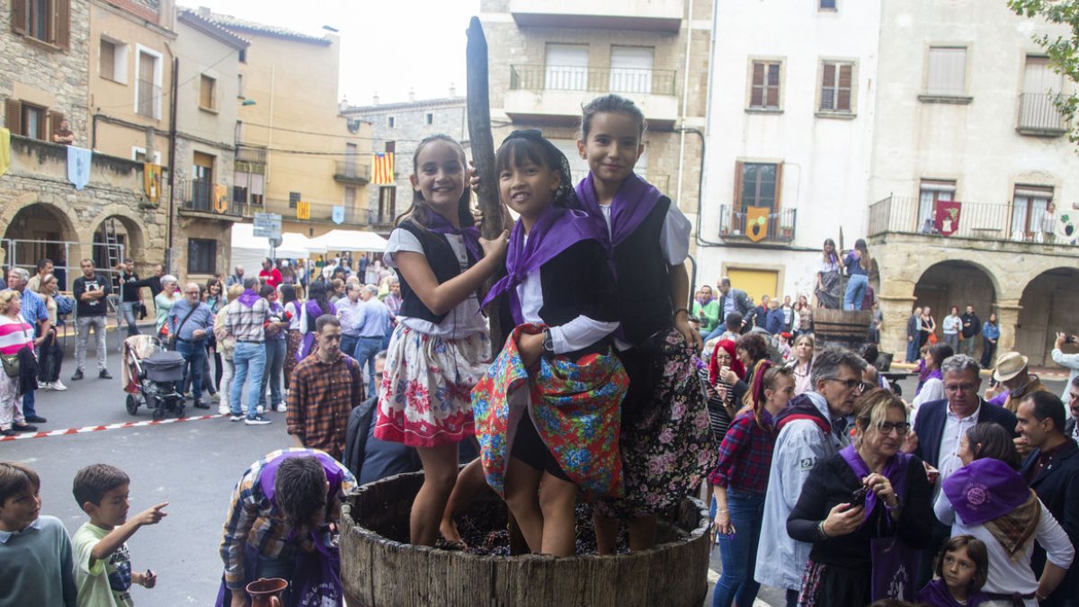 Tres nenes trepitjant raïm a la plaça Major, que es va omplir de visitants ahir al migdia amb l’acte central de la Gran Piada. - LAIA PEDRÓS